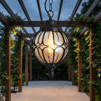 Outdoor Glass Globe Pendant Light – hanging under a pergola on a garden path