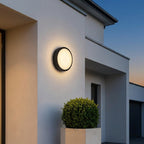 Round Outdoor LED Porch Wall Light – mounted beside a plant pot at dusk