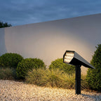 Adjustable Solar Garden Spotlight – lit beside a white garden wall at dusk