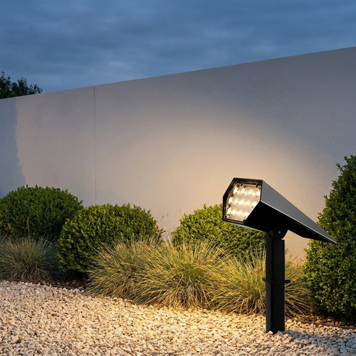 Adjustable Solar Garden Spotlight – lit beside a white garden wall at dusk