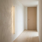 Wooden Up & Down LED Wall Light – lit on a hallway wall beside a door