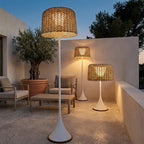 Woven Solar Outdoor Floor Lamp – lit among potted olive trees at dusk