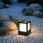 Square Black Solar Fence Post Light – lit on a gravel path among boulders