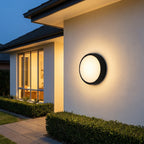 Round Outdoor LED Porch Wall Light – mounted beside a window at dusk
