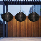 Black Rattan Outdoor Pendant Lantern – trio hanging above a wooden fence at dusk