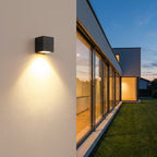 Square Outdoor Up & Down Wall Light – mounted on a wall beside glass doors at dusk