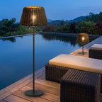 Woven Solar Outdoor Floor Lamp – lit beside a swimming pool at dusk