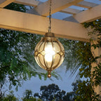Outdoor Glass Globe Pendant Light – hanging under a pergola among climbing vines