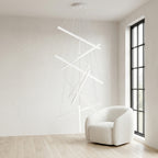 White Linear LED Chandelier – lit fixture beside an armchair near a window
