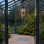 Outdoor Glass Ball Chandelier – hanging in a glasshouse doorway at dusk