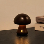 Otto Mushroom Table Lamp – lit on a bedside table beside stacked books, near-black finish
