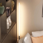 Slimline 360 LED Floor Lamp – lit beside a shelving unit and armchair