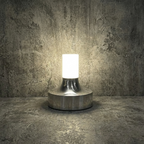 Ebba Table Lamp – lit against a stone wall, chrome finish