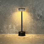 Halden Cordless Table Lamp – lit against a stone wall, black finish